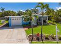 Inviting coastal home with a well-kept lawn, front brick walkway, garage, and screened porch, complemented by lush palms at 237 85Th St, Holmes Beach, FL 34217