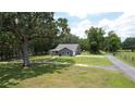 Aerial view of the house surrounded by a large lawn, mature trees, and a long driveway at 3287 Rackley Rd, Brooksville, FL 34604