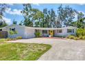 Charming home featuring a well-maintained yard, welcoming gravel driveway, and a bright yellow front door at 4151 Olive Ave, Sarasota, FL 34231