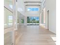 Bright living room featuring a soaring ceiling, clerestory windows, wood beams, and a sleek tile accent wall with shelving at 430 Pheasant Way, Sarasota, FL 34236