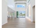 Inviting living room with a towering ceiling, wood beam accents, stylish tile wall with shelving, and sliding glass doors at 430 Pheasant Way, Sarasota, FL 34236