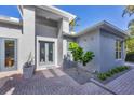 Contemporary front entrance with gray accents, brick walkway, and manicured landscaping at 4505 Camino Real, Sarasota, FL 34231