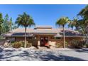 Charming clubhouse entrance with red doors, manicured landscaping, and symmetrical palm trees on a clear day at 4869 Village Gardens Dr # 189, Sarasota, FL 34234
