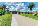 Beautiful exterior view of the home with a well-maintained lawn and a long driveway and blue skies at 5482 Globe Ter, North Port, FL 34286