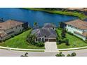 Beautiful aerial view of a home on the water featuring lush landscaping and a brick paved driveway at 5622 Arnie Loop, Lakewood Ranch, FL 34211