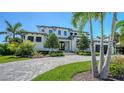 Elegant home with manicured lawn, mature trees, a circular paver driveway, and professionally installed landscaping at 612 Mourning Dove Dr, Sarasota, FL 34236