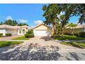 Inviting home with a brick-paved driveway leading to a two-car garage, complemented by manicured landscaping and a tile roof at 7716 Uliva Way, Sarasota, FL 34238