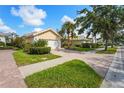 Residential street view showcasing a home with a brick driveway, mature landscaping, and well-maintained lawn at 7716 Uliva Way, Sarasota, FL 34238