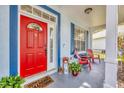 Inviting front porch features a red door, colorful flowers, and comfortable seating, creating a welcoming entrance at 11208 Blue Sage Pl, Lakewood Ranch, FL 34202