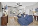 Cozy living room features a comfortable blue sofa, tile floors, a ceiling fan, and lots of natural light at 11208 Blue Sage Pl, Lakewood Ranch, FL 34202
