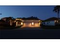 Exterior of a home at twilight, showcasing a three-car garage, illuminated landscaping, and inviting curb appeal at 12358 Lavender Loop, Bradenton, FL 34212