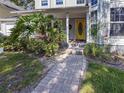 Inviting front entrance with brick walkway and lush landscaping leading to a bright yellow door at 2306 63Rd W St # 40, Bradenton, FL 34209