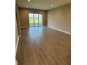 Bright living room featuring neutral walls, wood-look tile floors, and sliding glass doors at 24779 Buckingham Way, Port Charlotte, FL 33980