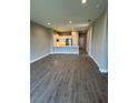 Open-concept space with wood-look flooring, flowing into the kitchen with a breakfast bar at 24779 Buckingham Way, Port Charlotte, FL 33980