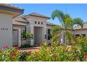 Stunning home exterior showcases a lush front garden with vibrant red flowers, a modern design, and a brick walkway at 3212 Signet Ct, Sarasota, FL 34240