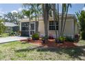 Back exterior view featuring tropical landscaping and a glimpse of the cozy screened patio at 3411 15Th E St, Ellenton, FL 34222