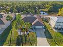 Aerial view of a charming single Gathering home featuring lush tropical landscaping, an attached two car garage and screened in patio at 3415 Knox Ter, Port Charlotte, FL 33948