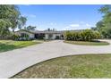 Charming single-story home featuring a circular driveway, mature trees, and lush landscaping at 3810 Hidden River Rd, Sarasota, FL 34240