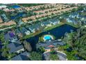 Aerial view shows community pool, lake, clubhouse, parking, and lots of greenery at 5681 Bidwell Pkwy # 104, Sarasota, FL 34233