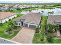 Aerial view of a beautiful home by a lake, featuring lush landscaping and a spacious three-car garage at 7327 Summerland Cv, Bradenton, FL 34202