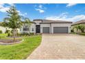 Beautiful home showcasing a well-manicured lawn, brick driveway, and a welcoming two-car garage at 7327 Summerland Cv, Bradenton, FL 34202