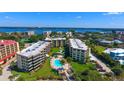 Aerial view of waterfront condos, a pool, and lush landscaping at 8779 Midnight Pass Rd # 506H, Sarasota, FL 34242