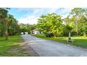 Long driveway leads to a well-maintained home surrounded by green lawns at 950 Trotter St, Nokomis, FL 34275