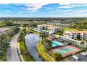 Aerial view of community featuring a pool, tennis court, pond, and green spaces at 9630 Club South Cir # 6303, Sarasota, FL 34238