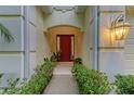Inviting entryway with a bright red door framed by lush greenery and stylish outdoor lighting at 12175 Maple Ridge Dr, Parrish, FL 34219