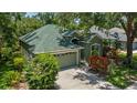 Charming one-story home with lush landscaping, green exterior, and a two-car garage at 135 Tall Trees Ct, Sarasota, FL 34232