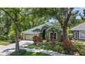 Charming one-story home with lush landscaping, green exterior, and a two-car garage at 135 Tall Trees Ct, Sarasota, FL 34232