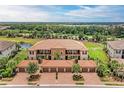 Beautiful building with terracotta tile roof, garages, lush landscaping, and lake view in the background at 13710 Messina Loop # 201, Bradenton, FL 34211