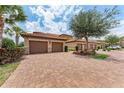 View of three garages with brick-paved driveway and landscaping at 13710 Messina Loop # 201, Bradenton, FL 34211