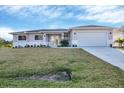 Inviting one-story home showcasing a manicured lawn, fresh landscaping, and a two-car garage at 14065 Paris Ln, Port Charlotte, FL 33981