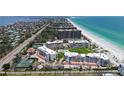 Aerial view of beachfront condos with beautiful beaches, lush landscaping, tennis courts, and a pool at 1465 Gulf Of Mexico Dr # 502, Longboat Key, FL 34228