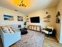 Bright living room featuring modern decor, light colored sofa, accent chair, and a media center at 15207 Searobbin Dr, Lakewood Ranch, FL 34202