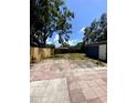 Large backyard featuring a wooden fence, mature trees, and spacious patio area at 1947 Los Lomas Dr, Clearwater, FL 33763