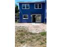 Rear exterior view with sliding glass door and patio, showcasing the blue facade and backyard access at 1947 Los Lomas Dr, Clearwater, FL 33763