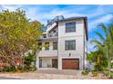 Three-story home featuring a metal roof, wood garage door, and lush landscaping at 421 Alamanda Rd, Anna Maria, FL 34216