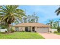 Inviting single-story home featuring a well-manicured lawn, palm tree, and attached two-car garage at 5307 Kenvil Dr, North Port, FL 34288