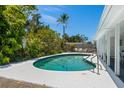 Private backyard featuring a sparkling kidney-shaped pool surrounded by lush landscaping and patio area at 6203 11Th W Ave, Bradenton, FL 34209