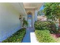 Inviting home entryway with decorative plants, a tiled walkway, and a charming arched window above the door at 7023 Woodside Oaks Cir # 1, Sarasota, FL 34231