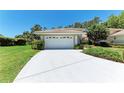 Home exterior featuring a white garage door, tiled roof, and well-maintained landscaping on a sunny day at 7023 Woodside Oaks Cir # 1, Sarasota, FL 34231