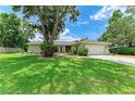 Charming single-story home with a lush green lawn, mature trees, and a paved driveway leading to a two-car garage at 7023 Woodside Oaks Cir # 1, Sarasota, FL 34231