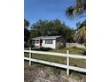 Single-story home with a bright red front door and a white fence in the front yard at 7109 28Th E St, Sarasota, FL 34243