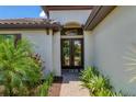Elegant double front door with glass panels, complemented by lush landscaping and a brick walkway at 8020 Clearwater Ct, Sarasota, FL 34241