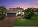 Charming single-story home featuring a tile roof, brick driveway, and a well-manicured front yard at twilight at 12856 Sorrento Way, Bradenton, FL 34211