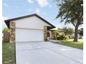 Single-story home with a two-car garage, stone veneer accents and driveway at 2477 Wood Oak Dr, Sarasota, FL 34232