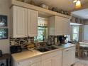 Charming kitchen featuring white cabinets, a mosaic backsplash, and an undermounted double sink at 4027 Allure Ln, North Port, FL 34287
