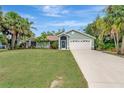 Attractive single-story home with a lush green lawn, tropical palm trees, and an attached two-car garage at 4322 Concert St, Port Charlotte, FL 33948
